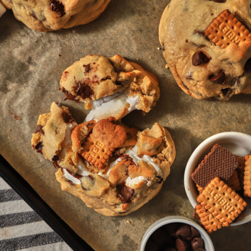 s'mores stuffed cookies on a parchment paper lined baking sheet.