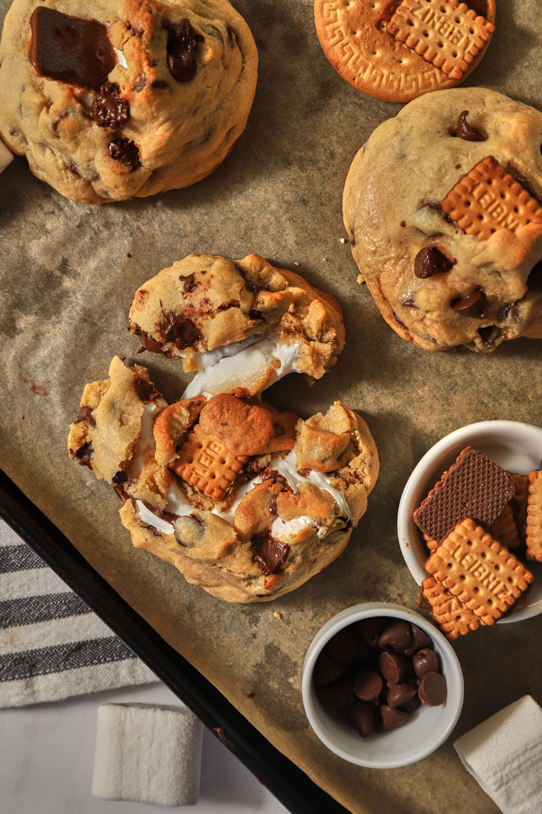 s'mores stuffed cookies on a parchment paper lined baking sheet.