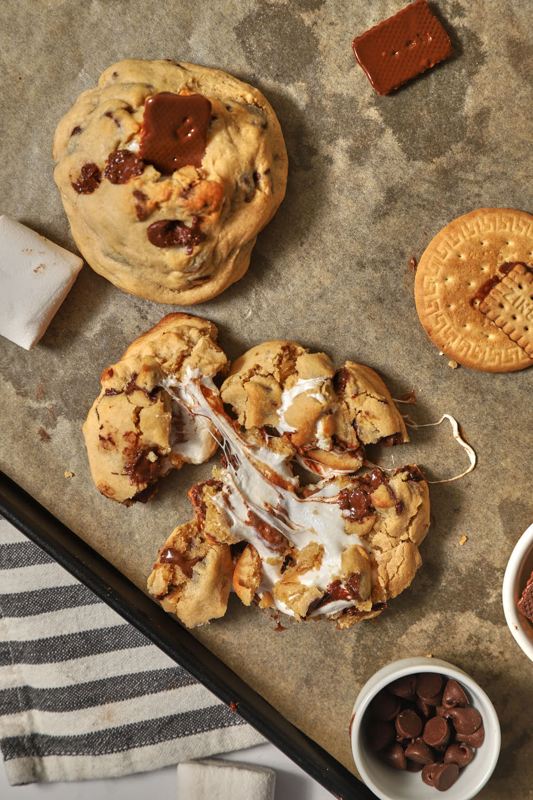 a gooey marshmallow stuffed giant chocolate chip cookie on parchment paper.