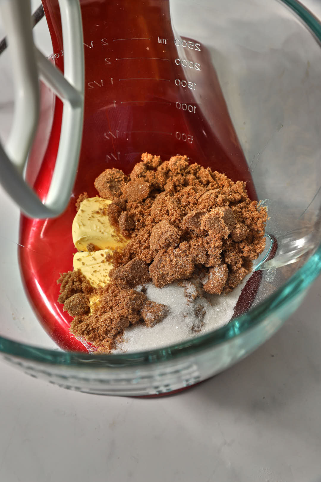 butter, brown and white sugar in a glass bowl of a stand mixer.