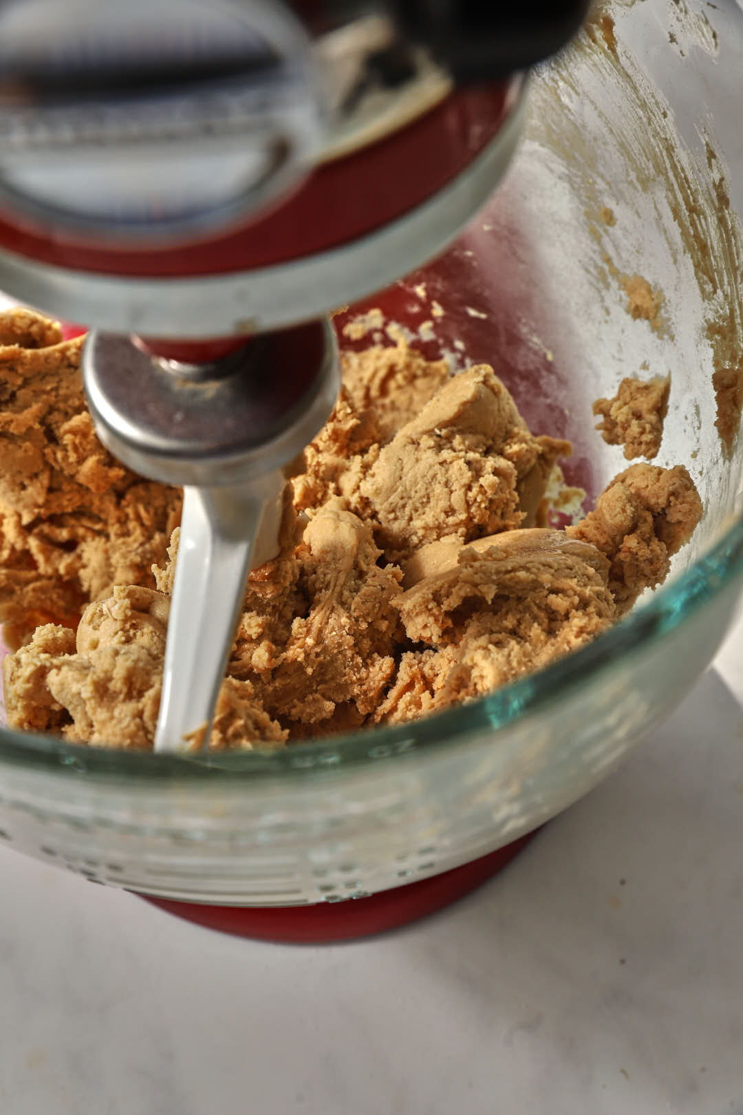 cookie dough mixed in the glass bowl of a stand mixer.