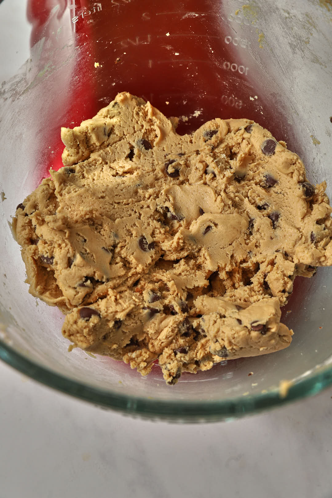 chocolate chip cookie dough mixed together in a glass stand mixer.