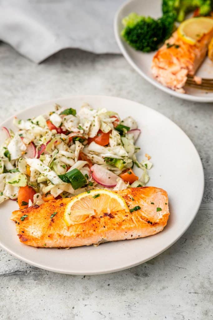 salmon with cabbage salad with another plate in background
