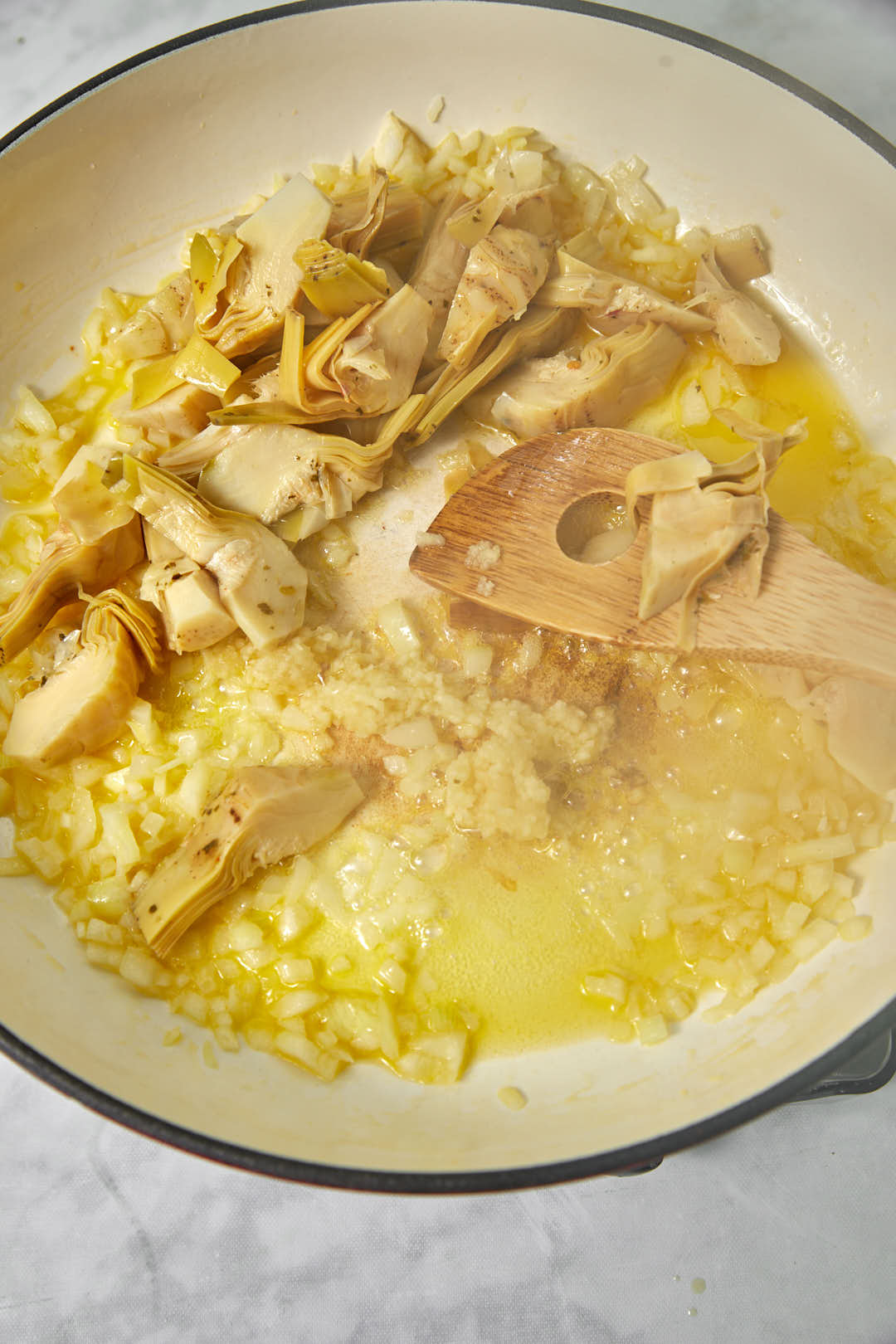 garlic and artichoke added to hot oil in a large skillet