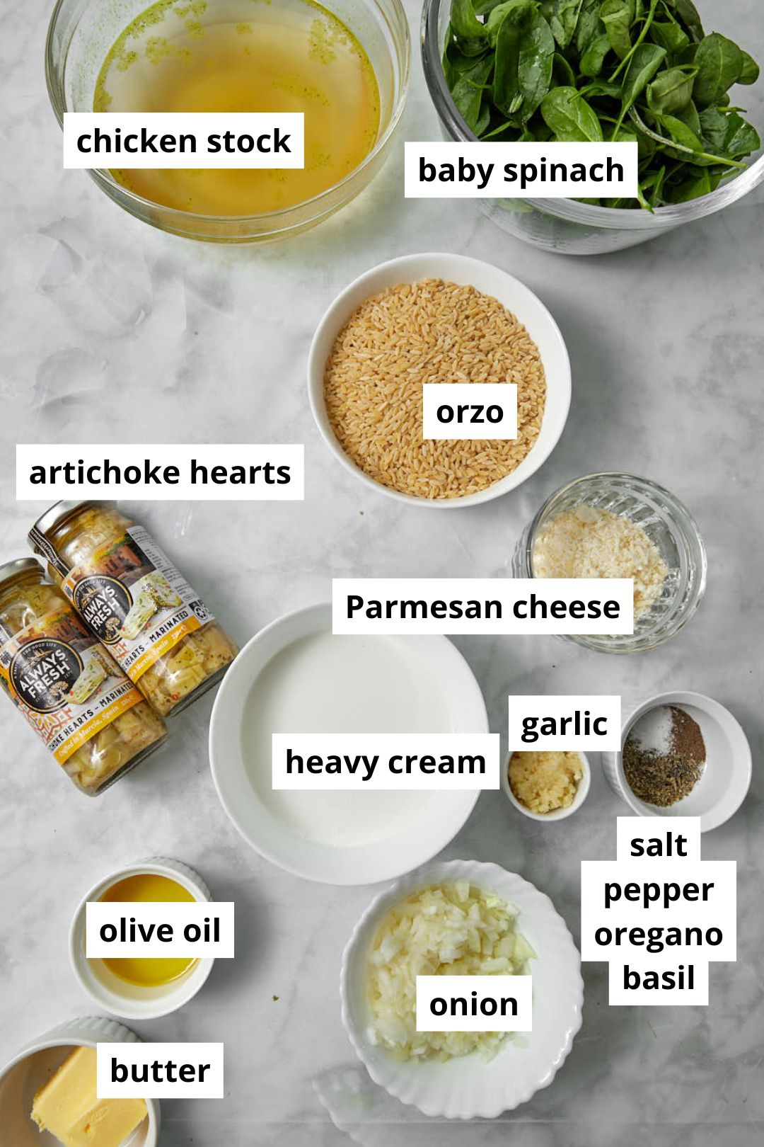 ingredients needed to make spinach artichoke orzo on white marble background.