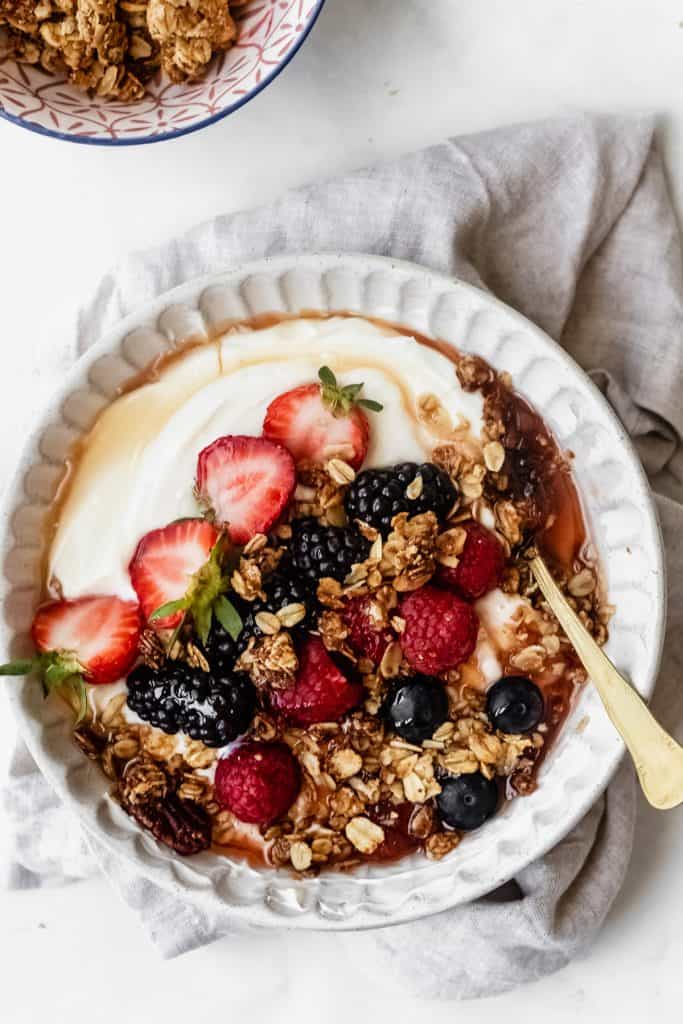 yogurt bowl with berries and granola on kitchen linen