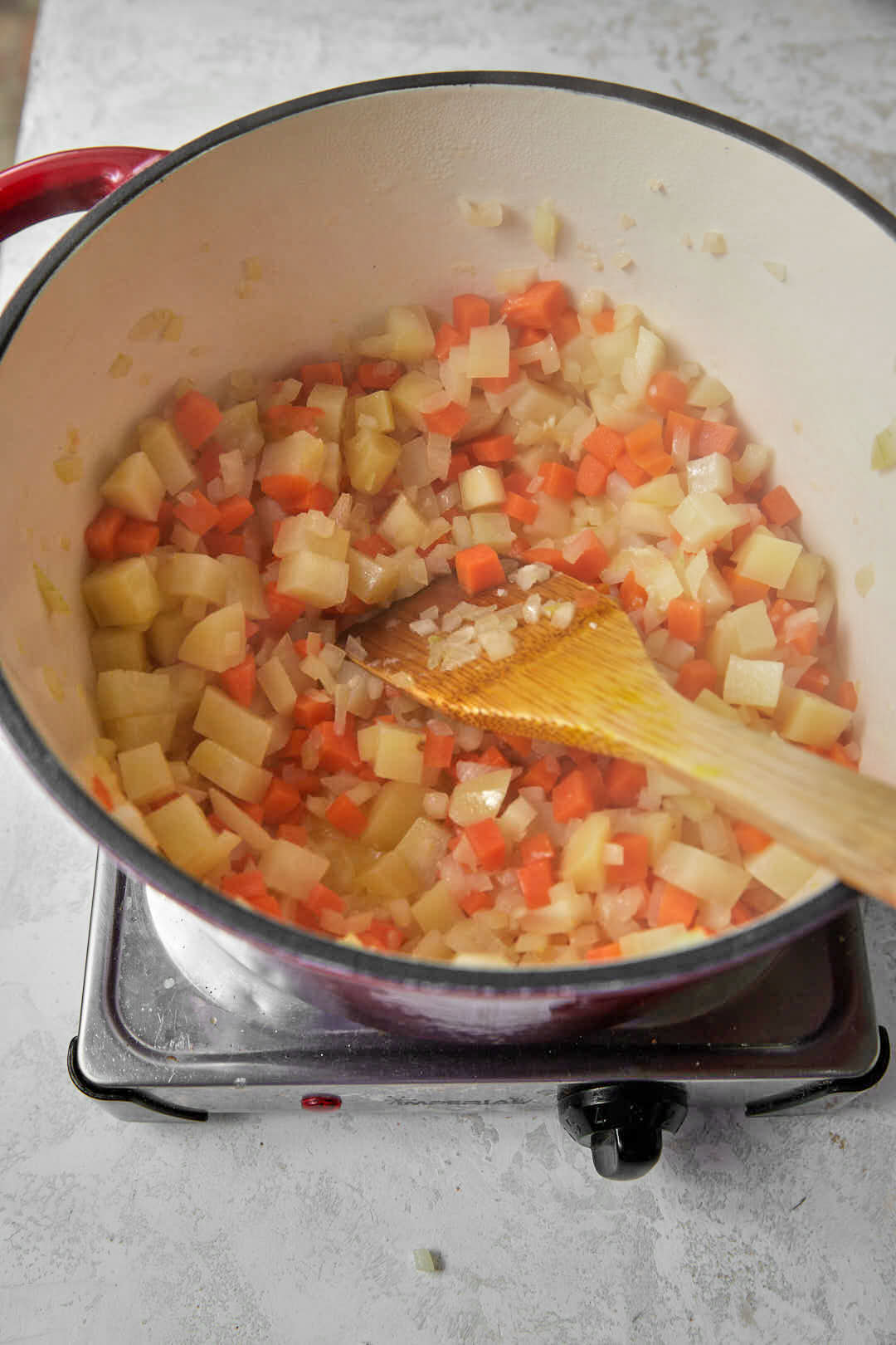 potatoes, carrots and onion cubes cooking in a hot saucepan for soup.