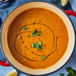 a big pot of turksih lentil soup with a drizzle of olive oil, and parsley on top, and a wedge of lemon on the side.