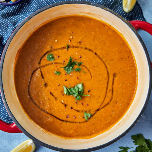 a big pot of turksih lentil soup with a drizzle of olive oil, and parsley on top, and a wedge of lemon on the side.
