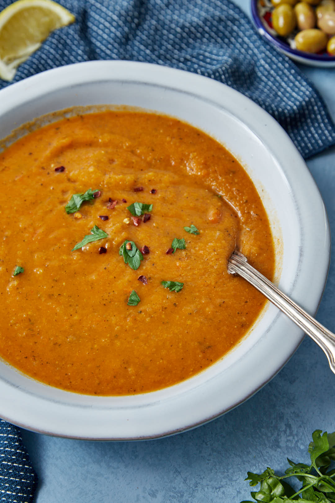 A close up photo of a bowl of Turkish lentil soup with a spoon taking out a scoop.
