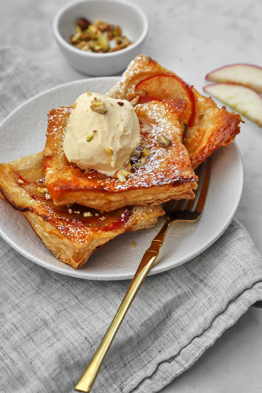 apple puff pastry squares with a scoop of vanilla ice cream and a fork.