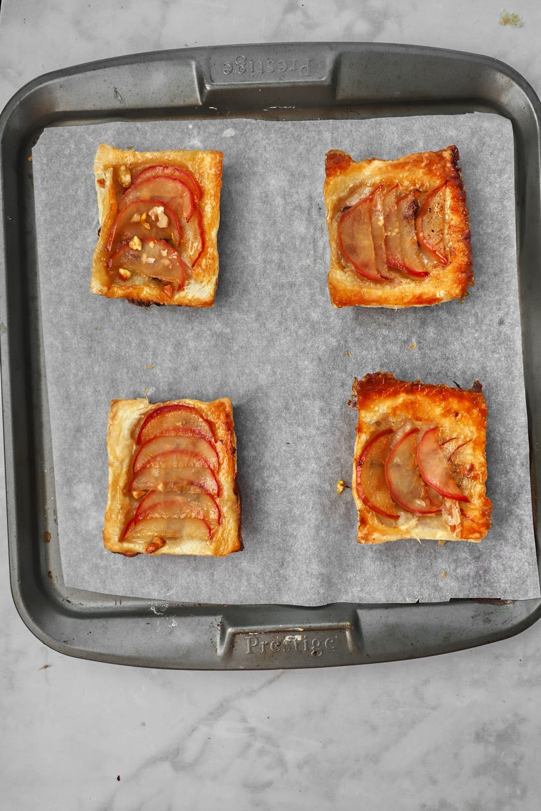 apple puff pastry squares on parchment paper lined baking sheet.