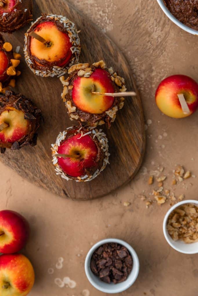healthy caramel apples on wooden board with toppings