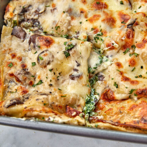 a slice of vegetable lasagna with bechamel being pulled out of the pan.