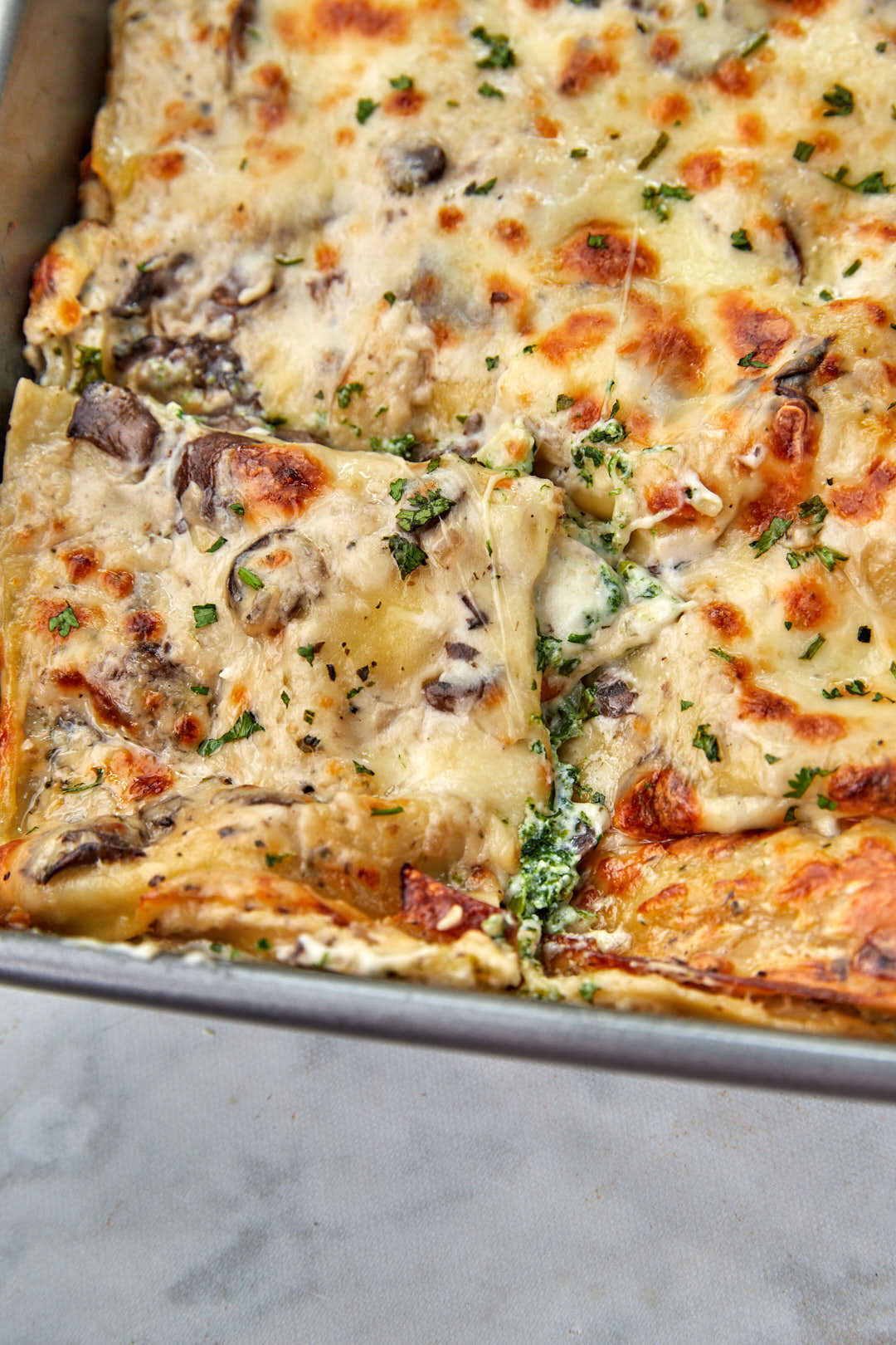 a slice of vegetable lasagna with bechamel being pulled out of the pan.