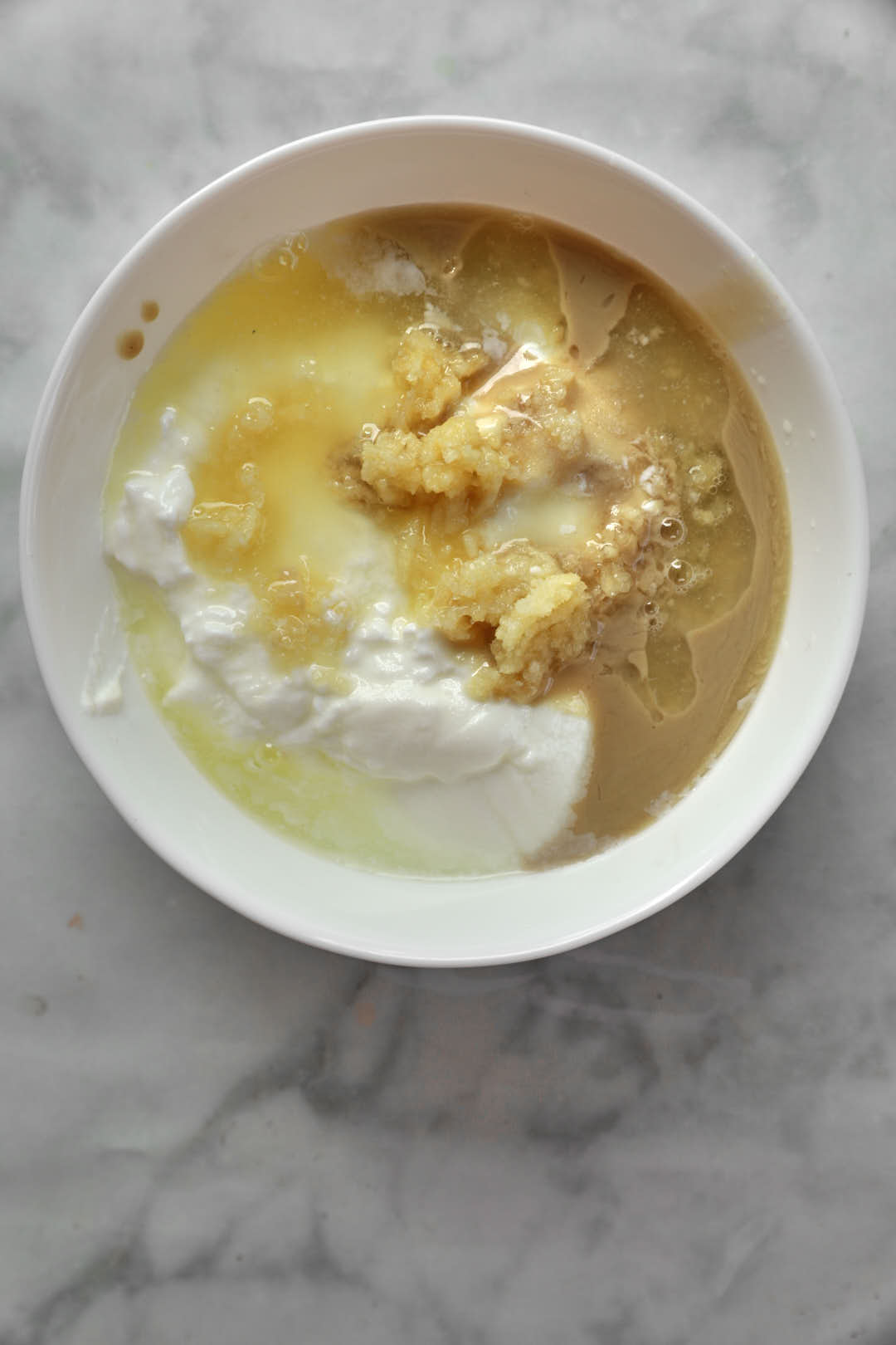 Ingredients for tahini yogurt in a small white bowl.