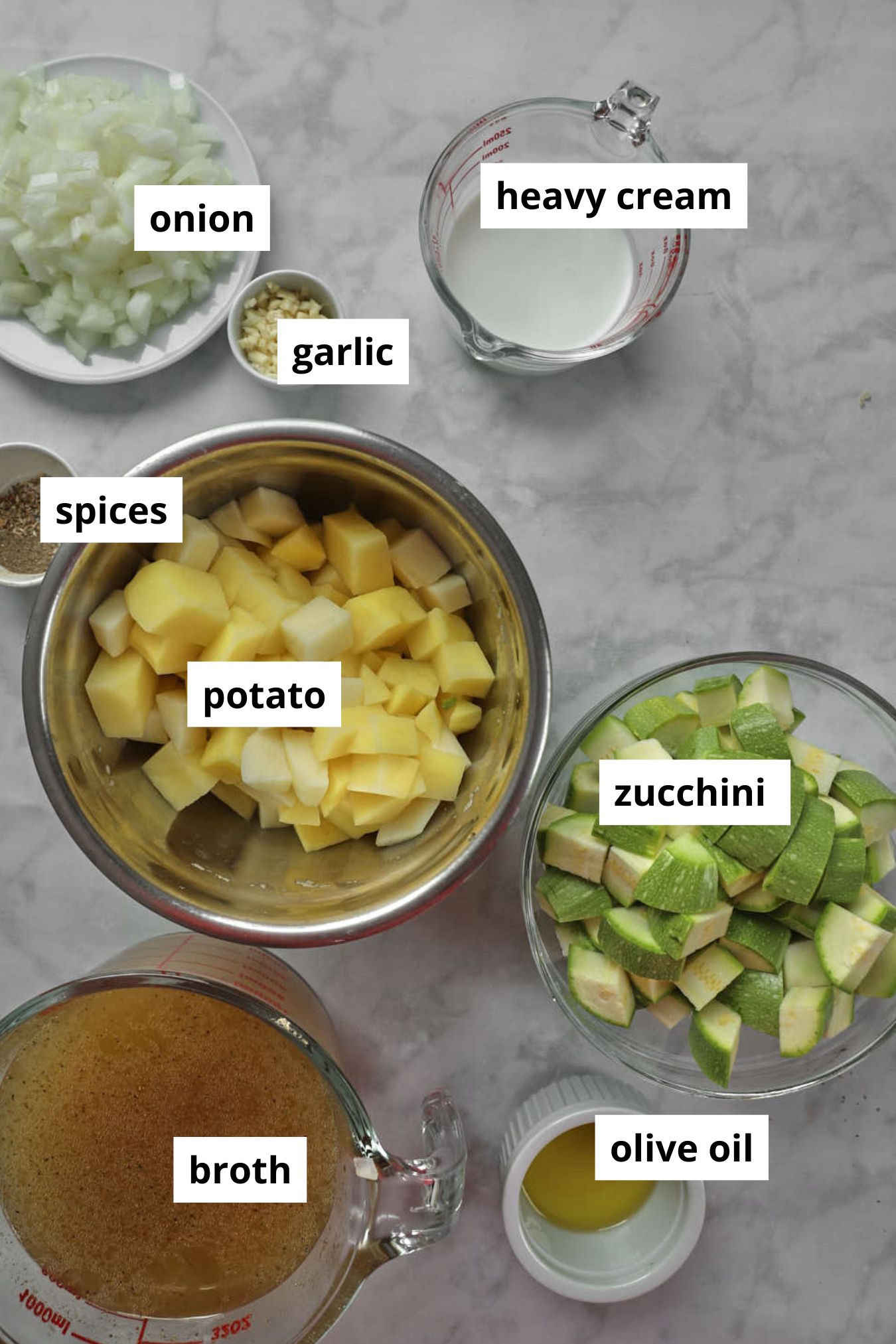 ingredients for zucchini potato soup on a white marble background